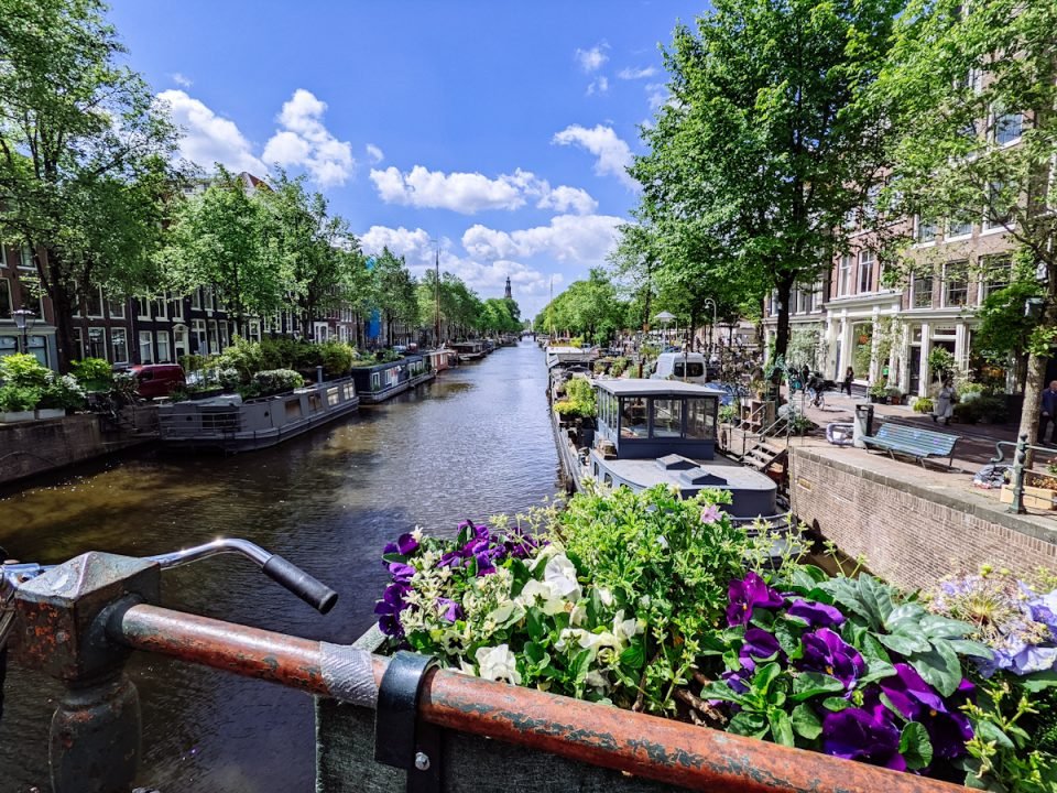 Vista su canale di Amsterdam da un ponte con viale alberato sulle sponde del corso d'acqua