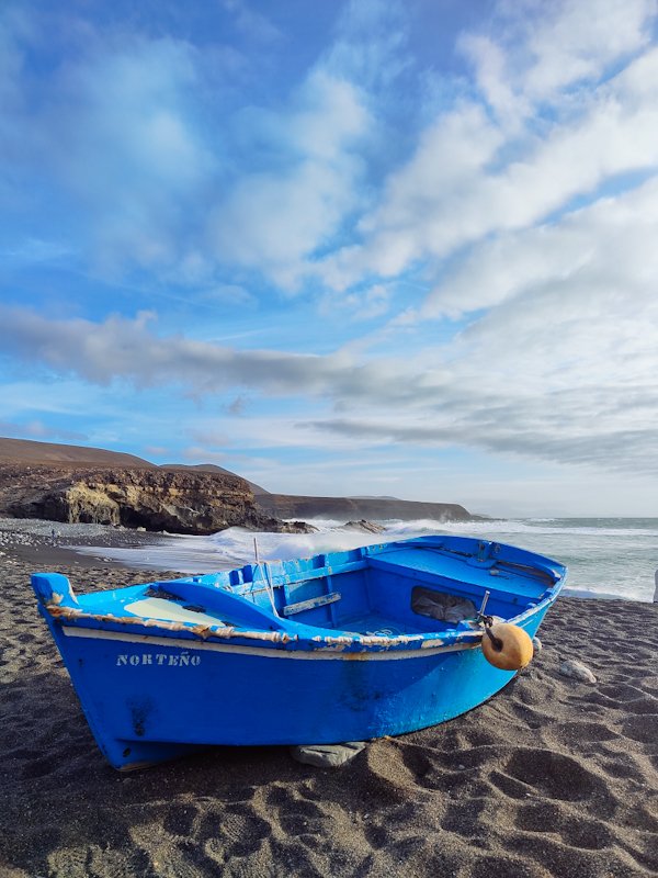 playa de ajuy Fotografia che raffigura la spiaggia nera della Playa de Ajuy con in primo piano una barchetta di legno azzurra