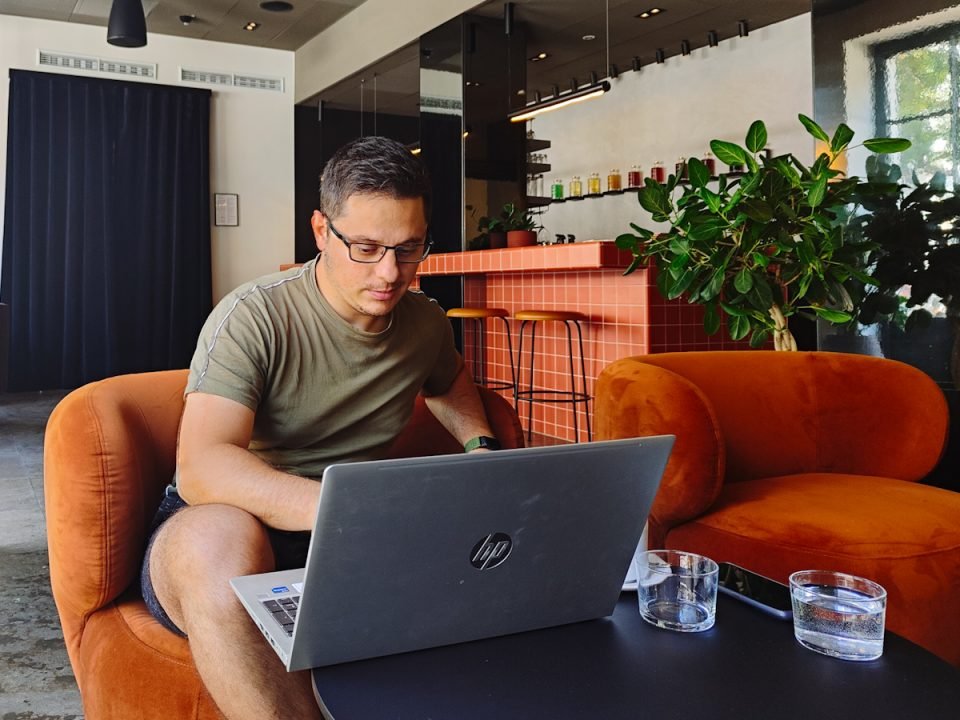 Immagine di Stefano che lavora con il suo laptop seduto su una poltrona di un coworking